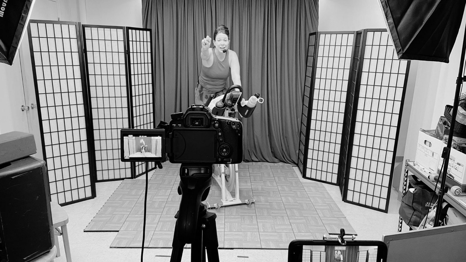 Filming a virtual fitness class, camera and lighting equipment alongside the spin bike